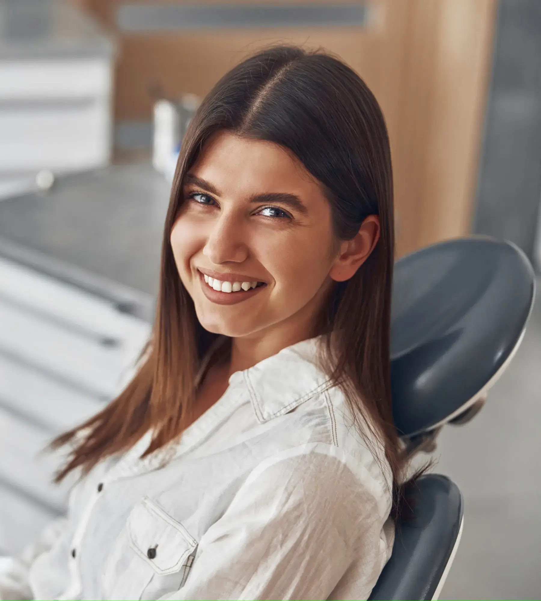 A woman sitting in a dentist chair smiling.
