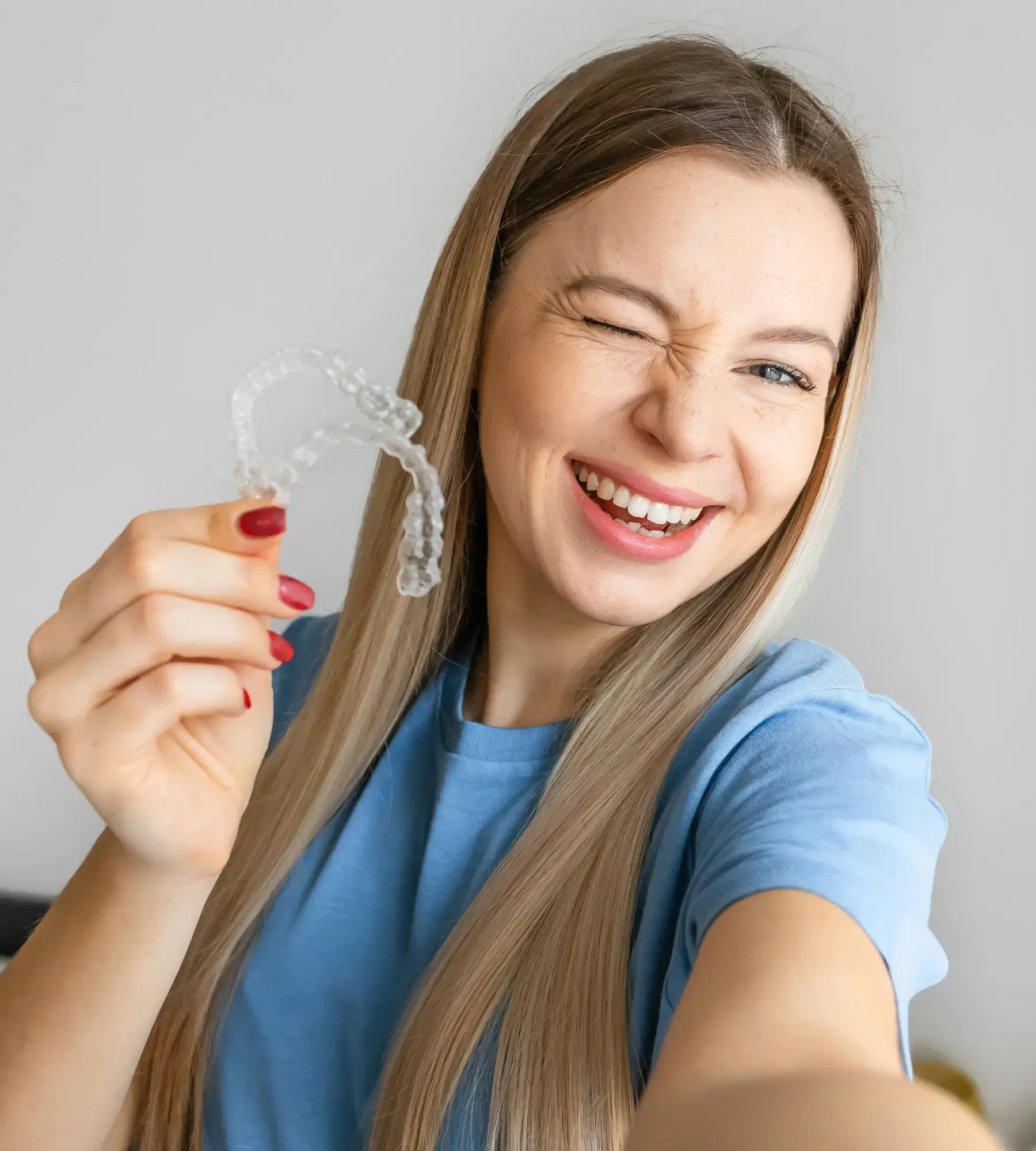 A woman smiles while holding a toothbrush in her hand.