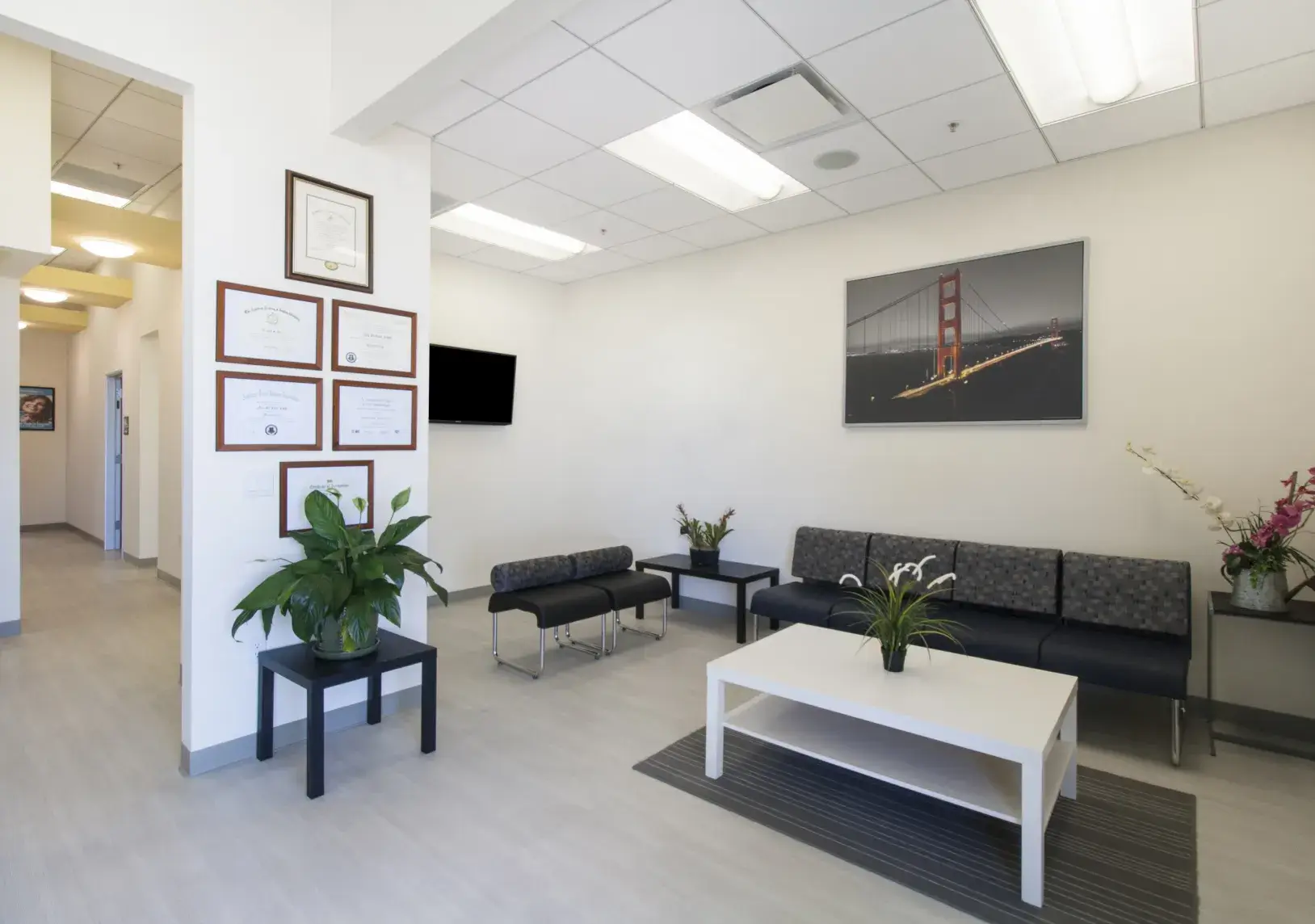 A waiting room with couches, tables, and pictures on the wall.