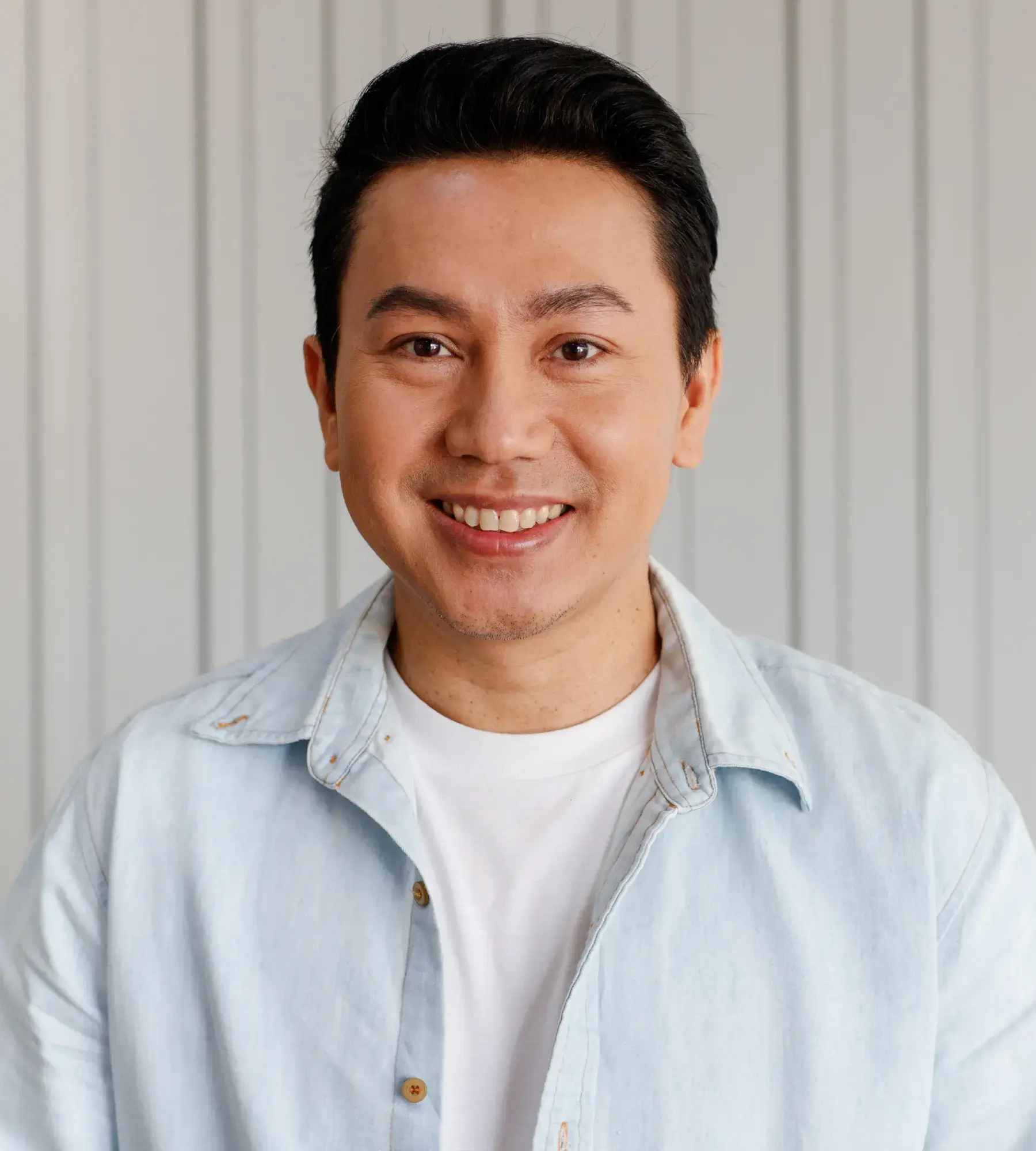 A man in a blue shirt smiling at the camera.