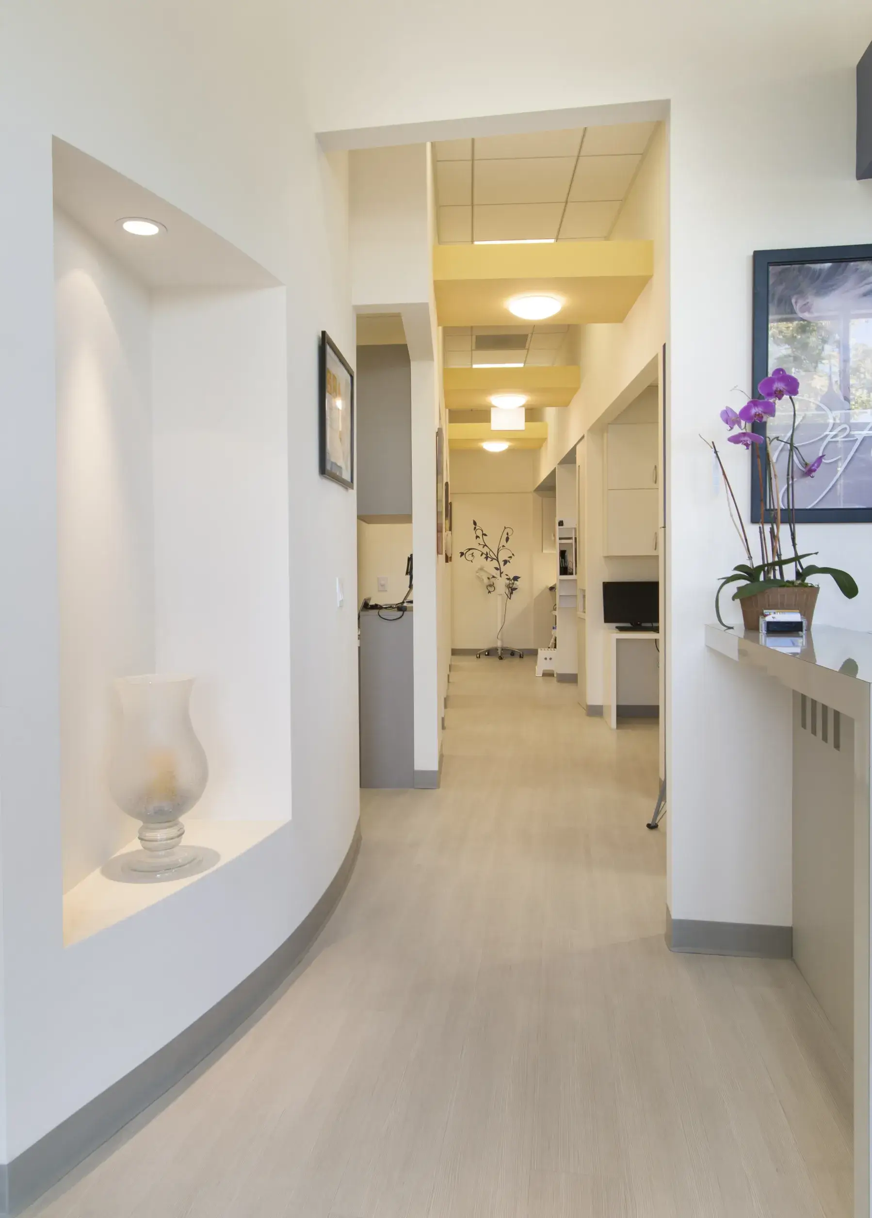 A long hallway with a vase of flowers on the wall.