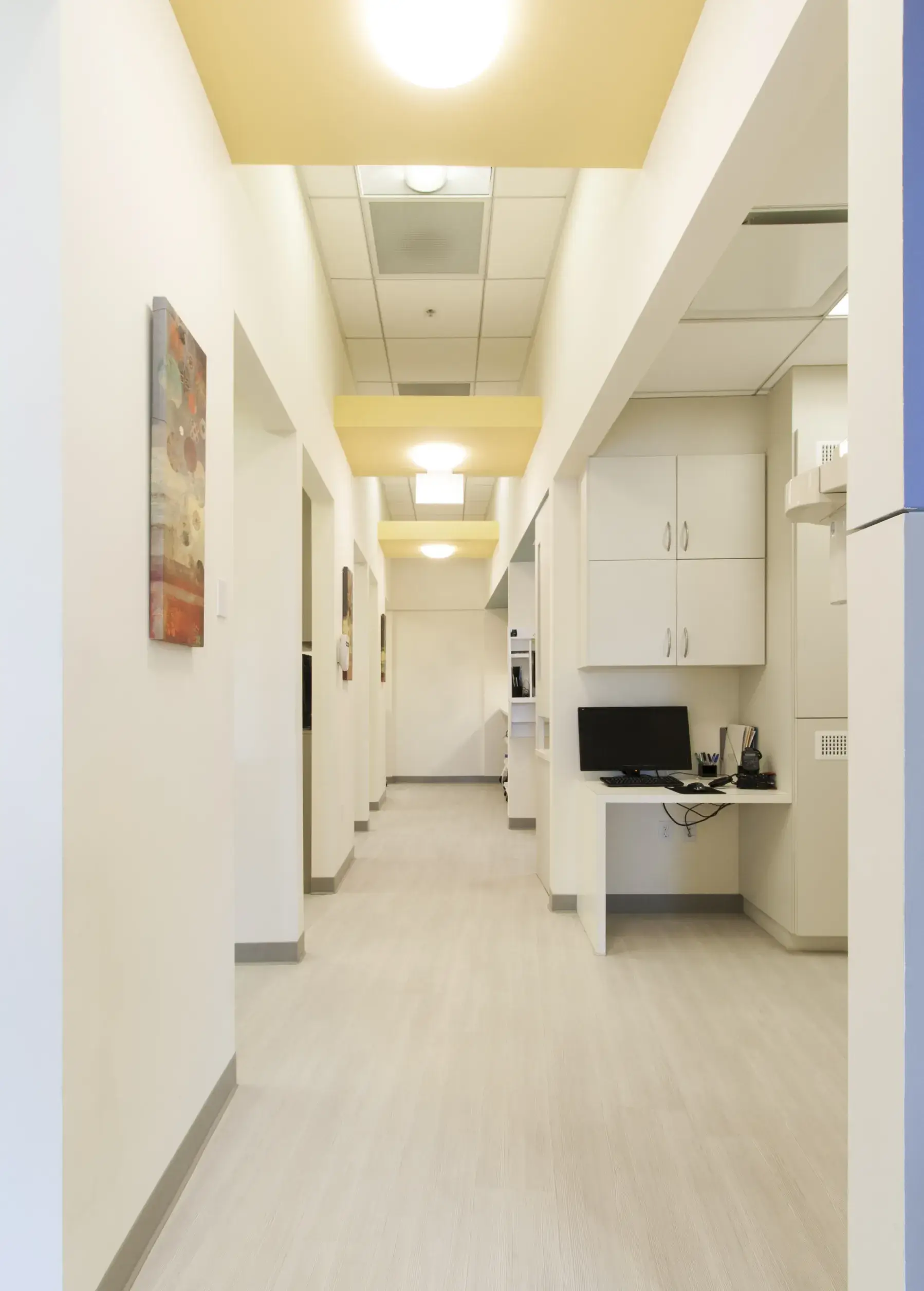 A long hallway with a laptop on the desk.